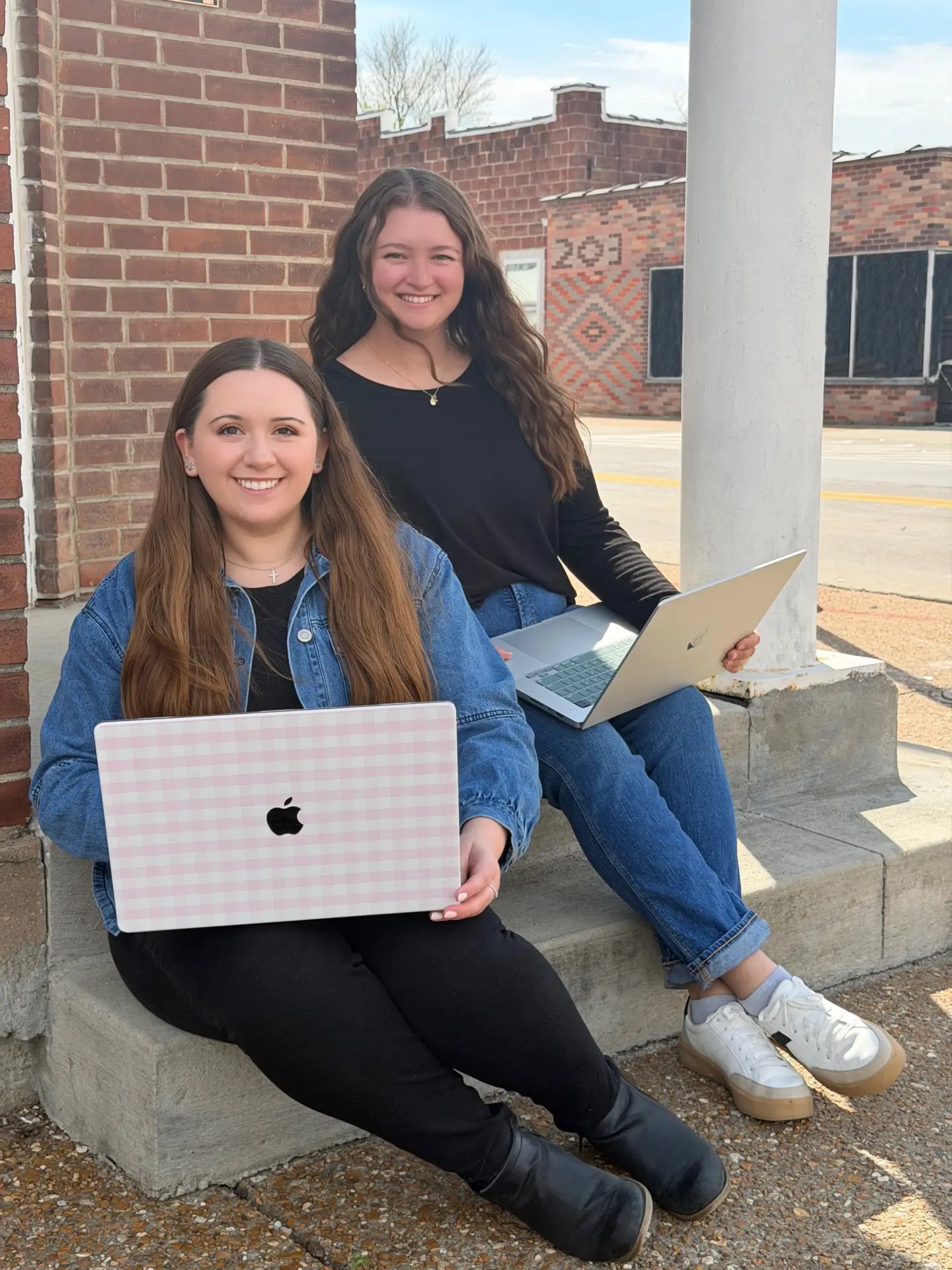 Elizabeth and Alesha sitting on the steps with laptops