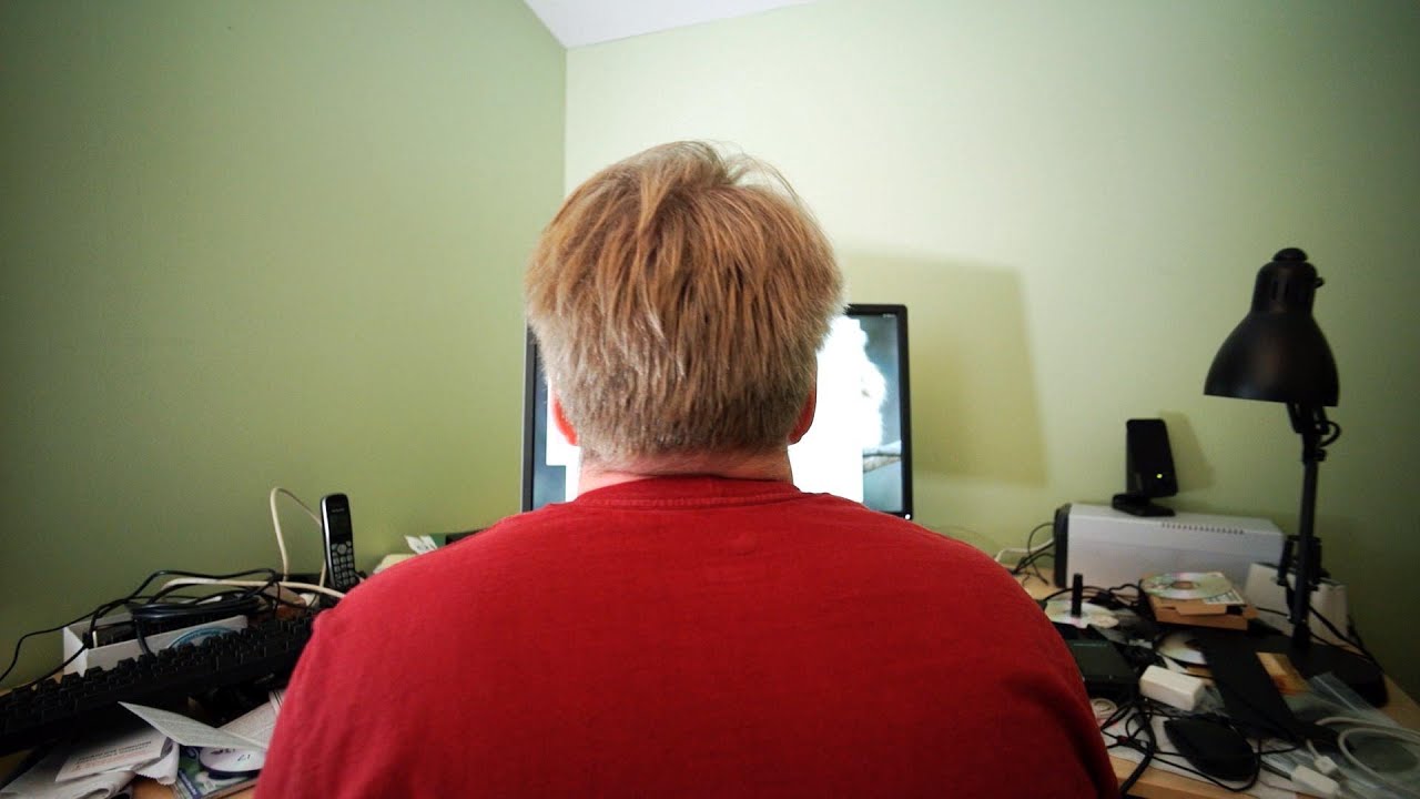 Vue de dos de Linus Torvalds assis à son bureau devant son écran d'ordinateur