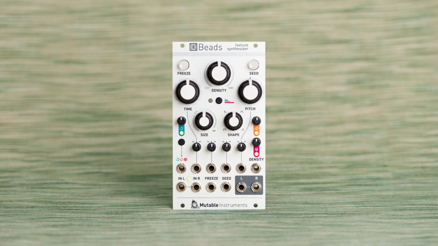 Façade avant blanche du module synthétiseur modulaire Beads de Mutable Instruments posé sur un tissu vert
