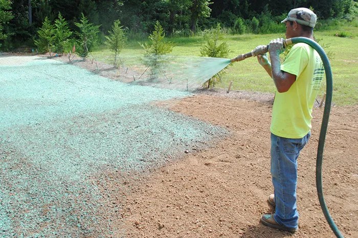 Worker applying hydroseeding on a lawn for grass growth and erosion control in a rural area.