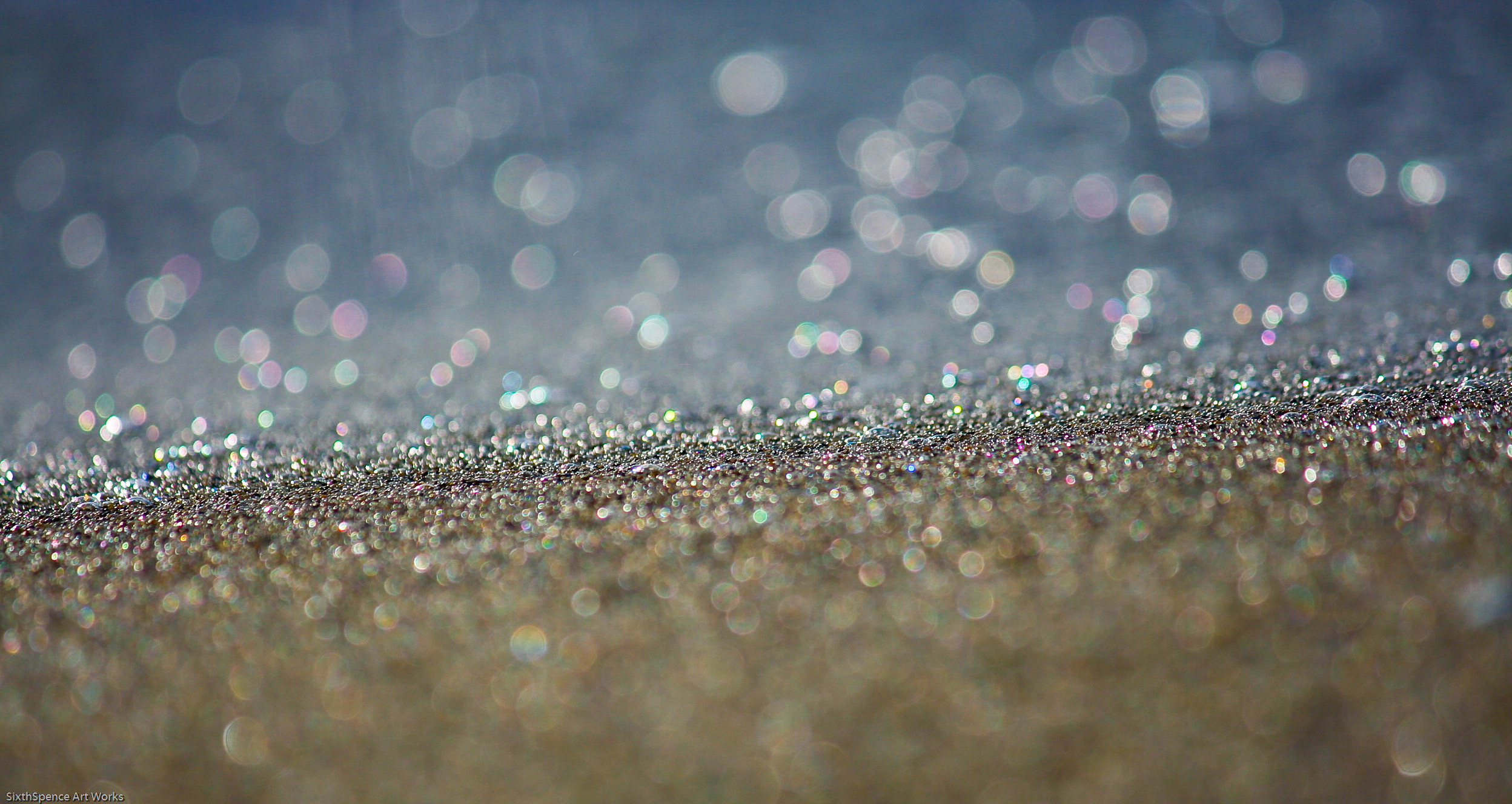Wet beach sand glistens and sparkles with a bokeh effect.