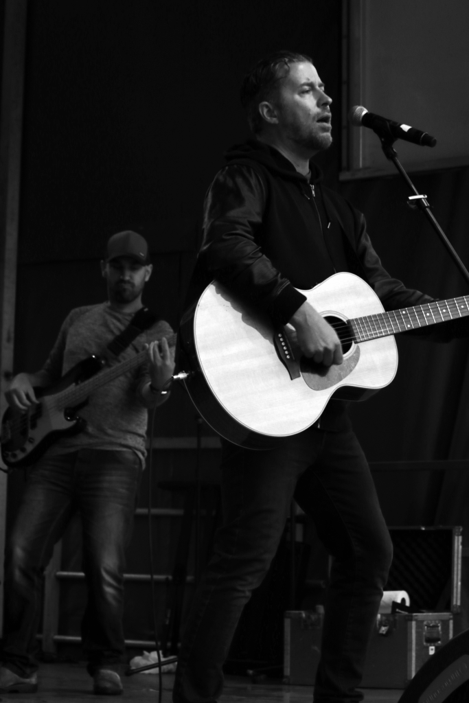 Black and white photo of Canadian rock singer Matthew Good performing on stage for the Recovery Week Festival in New Westminster, BC.