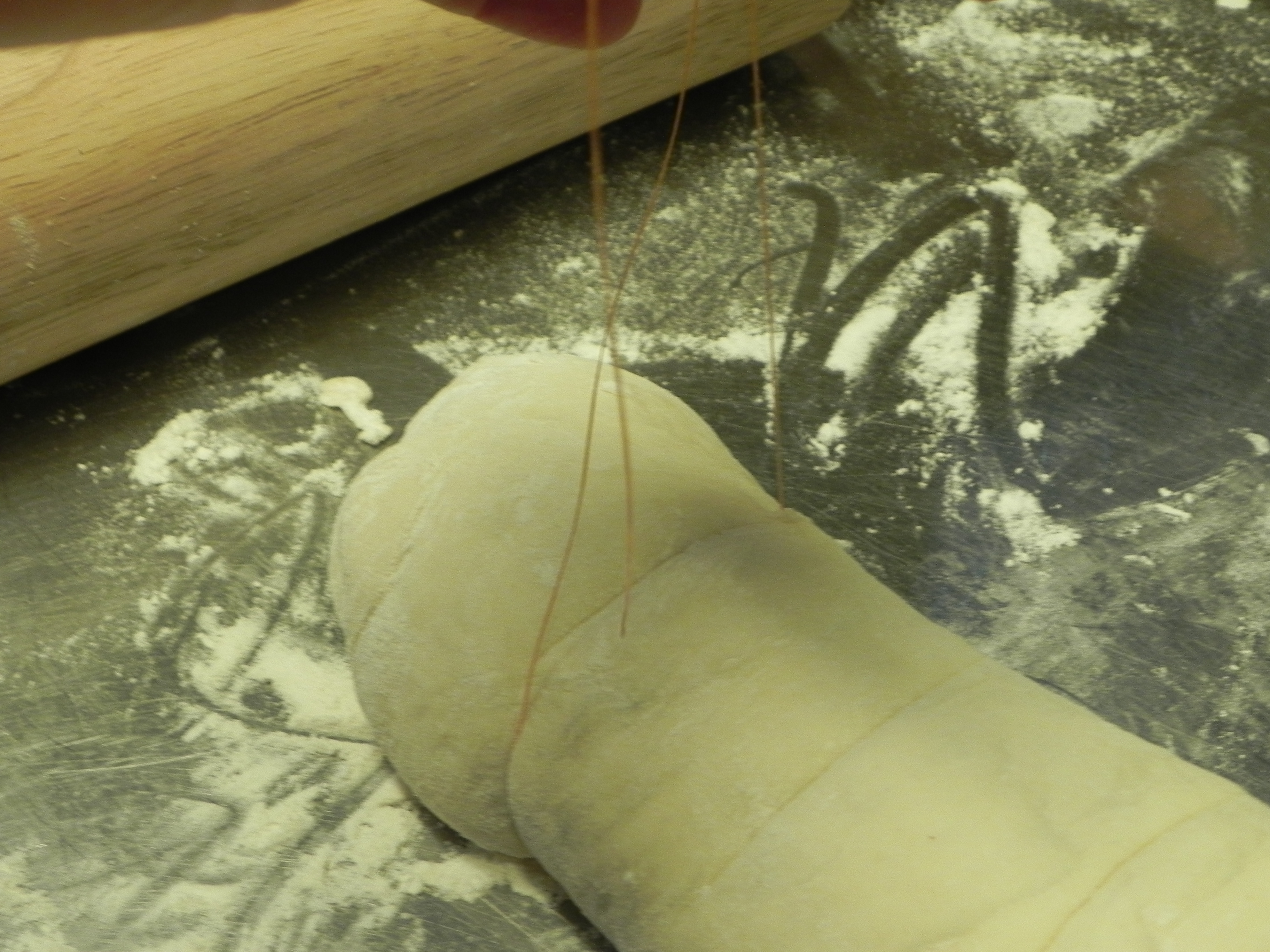 Wiggle the string under the dough and use it to cut into equal portions