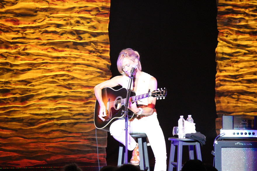 Acoustic performer against an amber backdrop