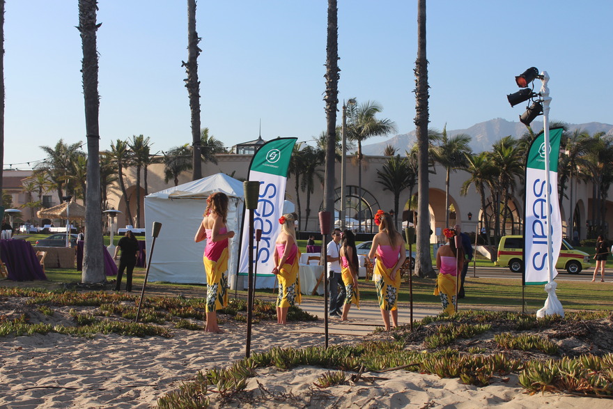 Performers beside branded flags on the sand