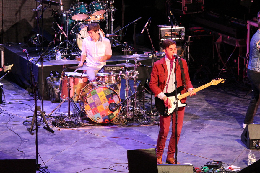 Guitarist in red beside the drum kit