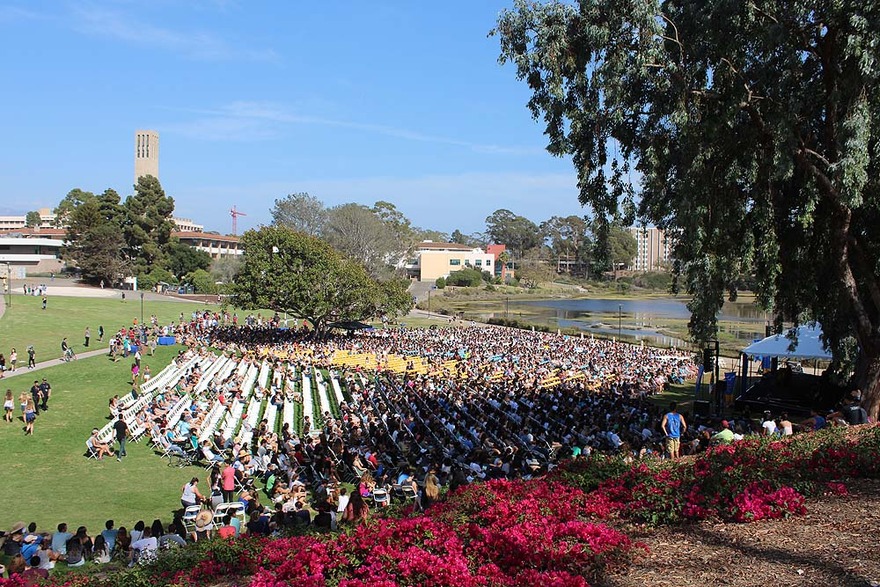 Outdoor ceremony with large seated crowd on a sunny day