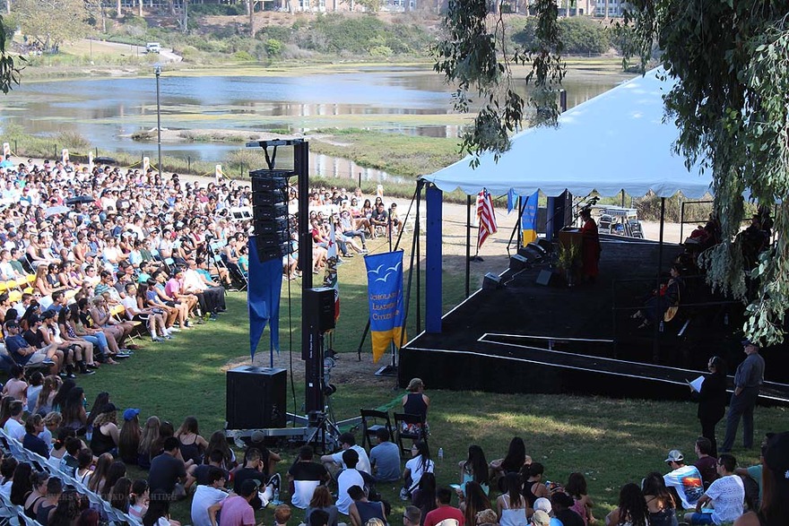 Campus lawn crowd facing a lagoon stage