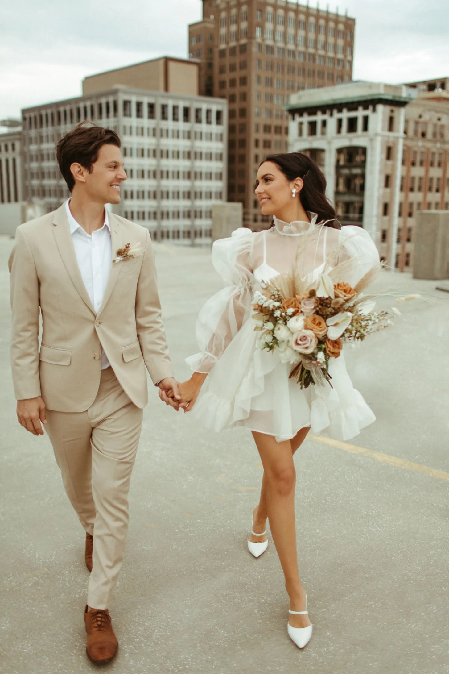 couple who planned to have custom alterations done to their wedding attire walking hand in hand on a rooftop where they held their ceremony
