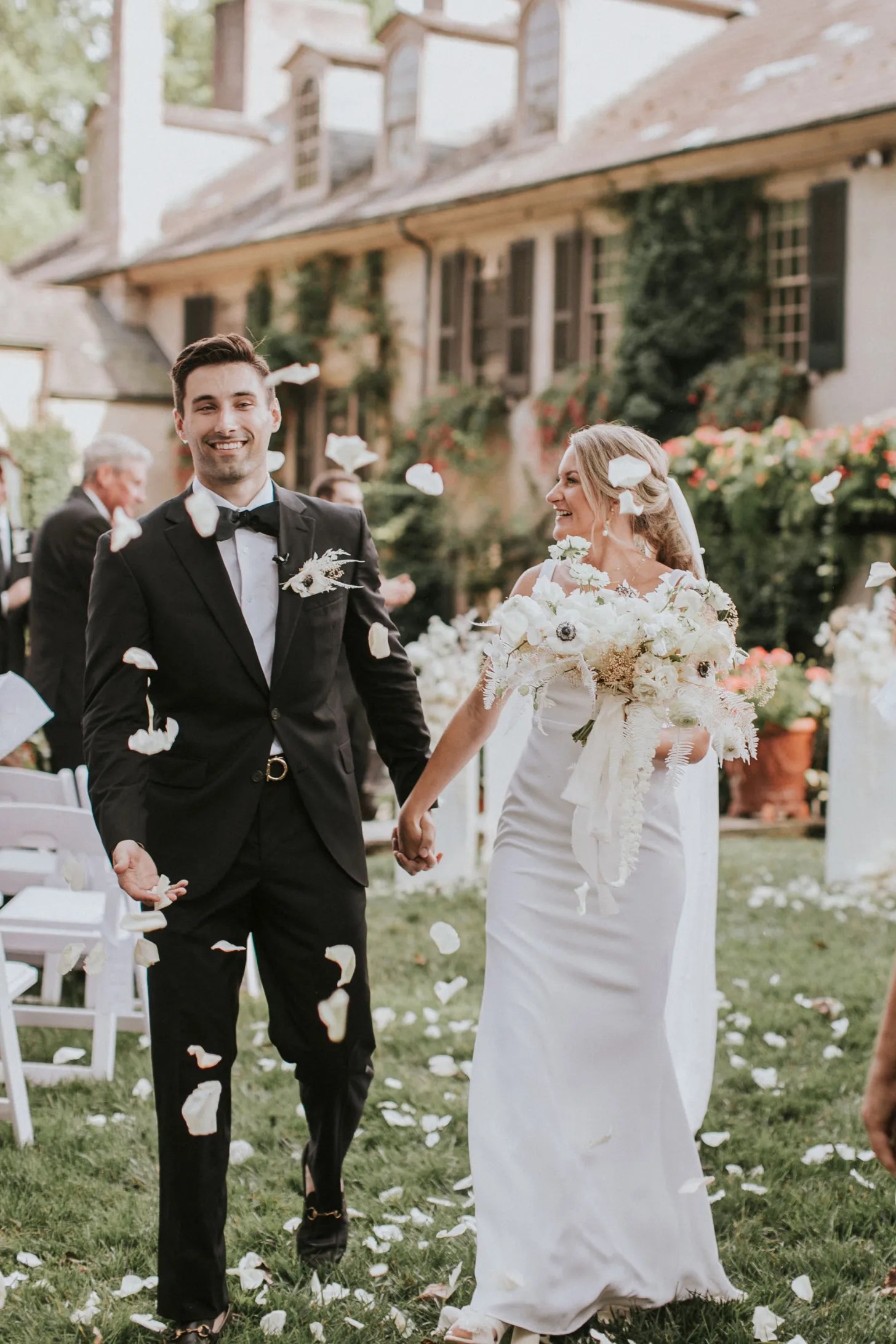 wedding planner and her husband walking through flower petals during their recessional