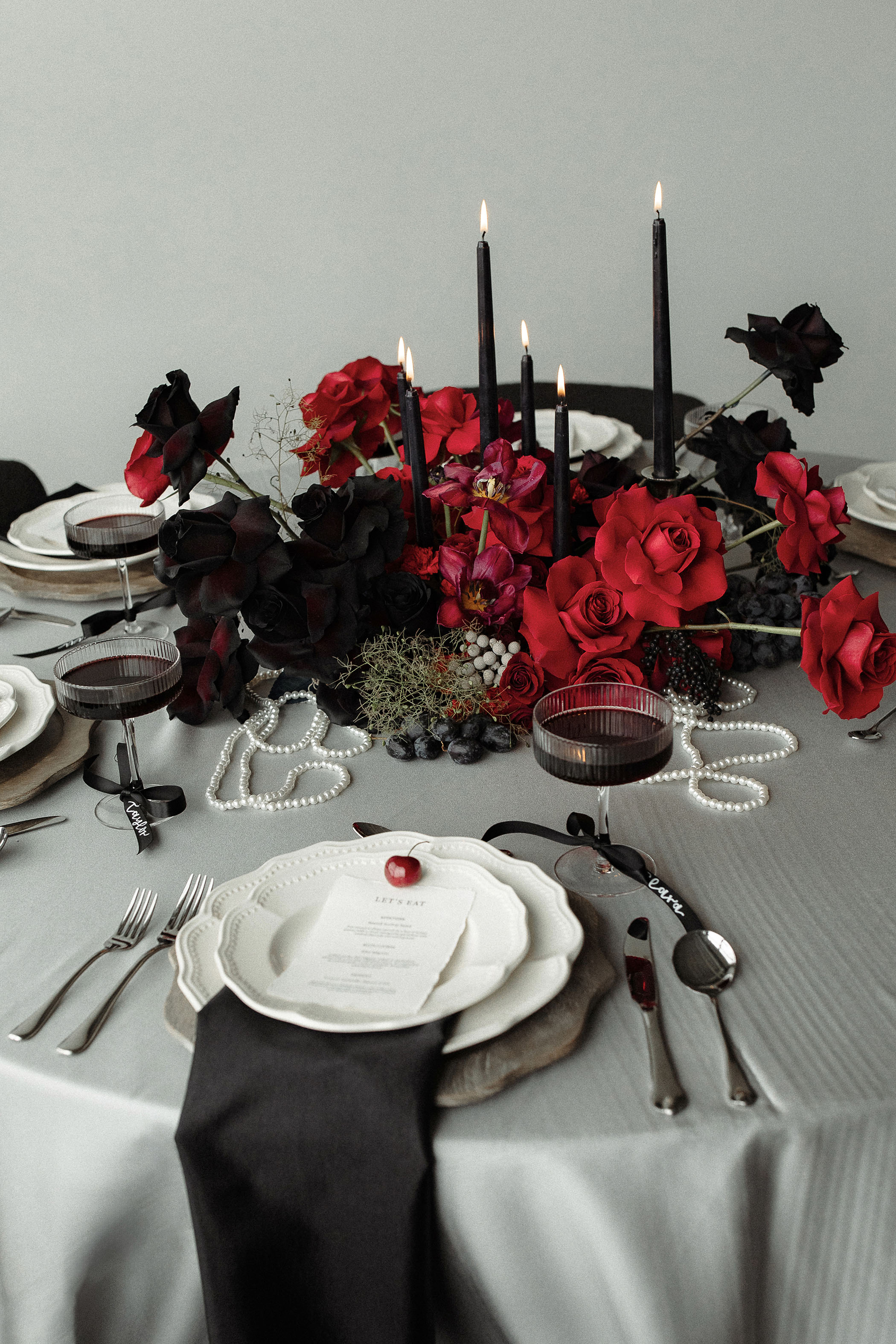 a black and red asymmetrical floral arrangement with black candlesticks protruding from it on a tablescape for a Taylor Swift TTPD inspired wedding photoshoot
