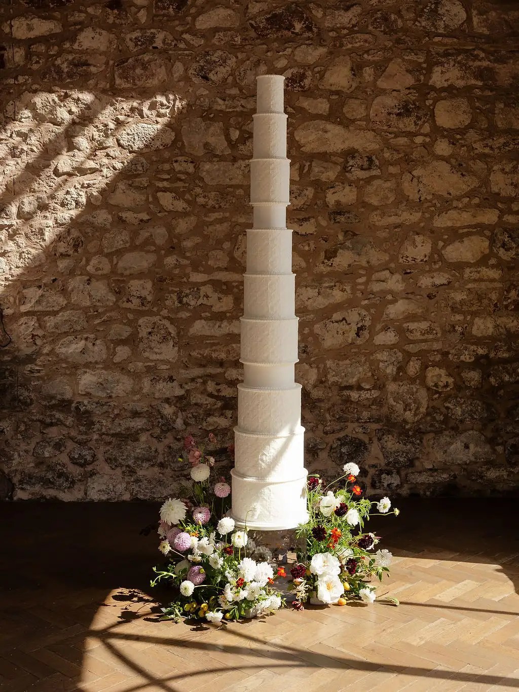 tall statement wedding cake with florals around it