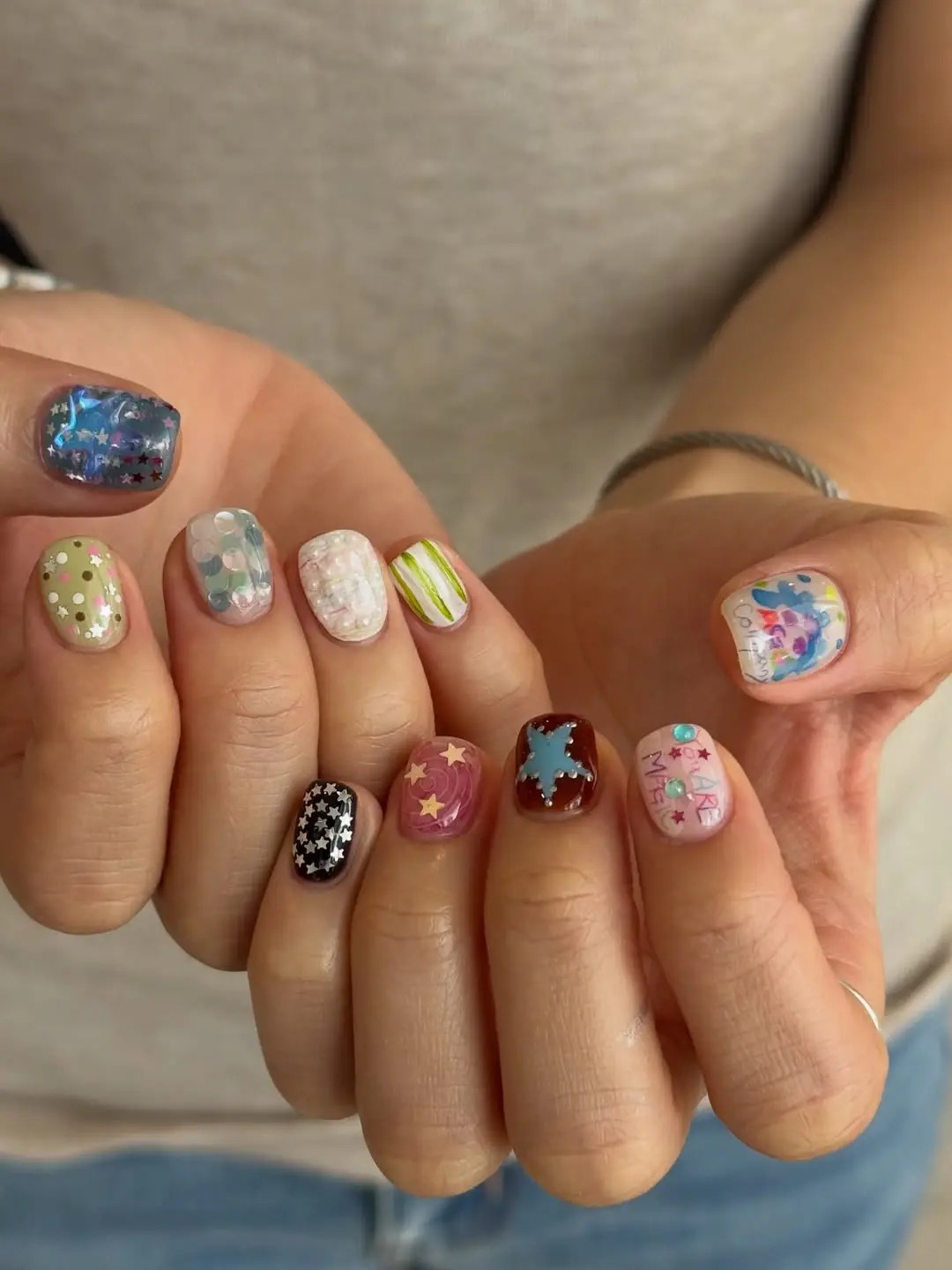 Playful mixed August nails with silver stars, hand-drawn doodles, pearls, and polka dots on short round nails