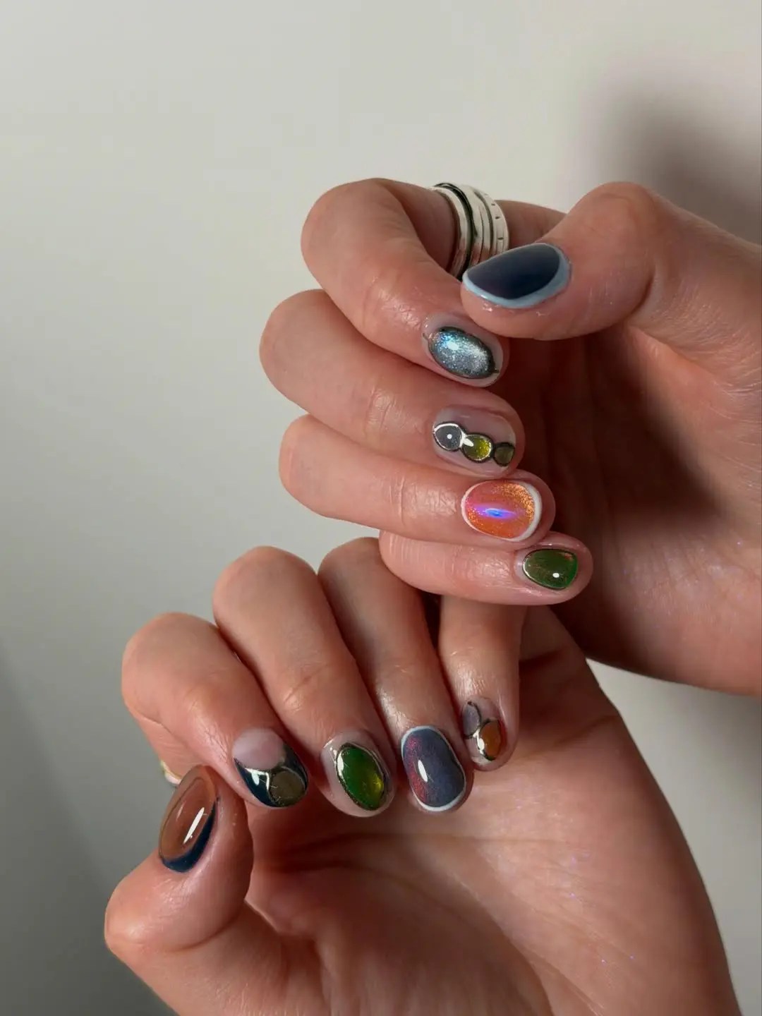 Gemstone cat eye nails with glossy emerald, garnet, and topaz ovals inside milky white borders on short nails