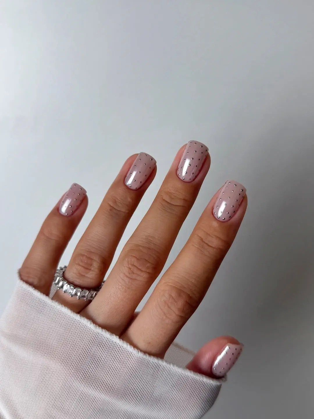 sheer pink nails with tiny silver stud microdots in neat rows on short square nails