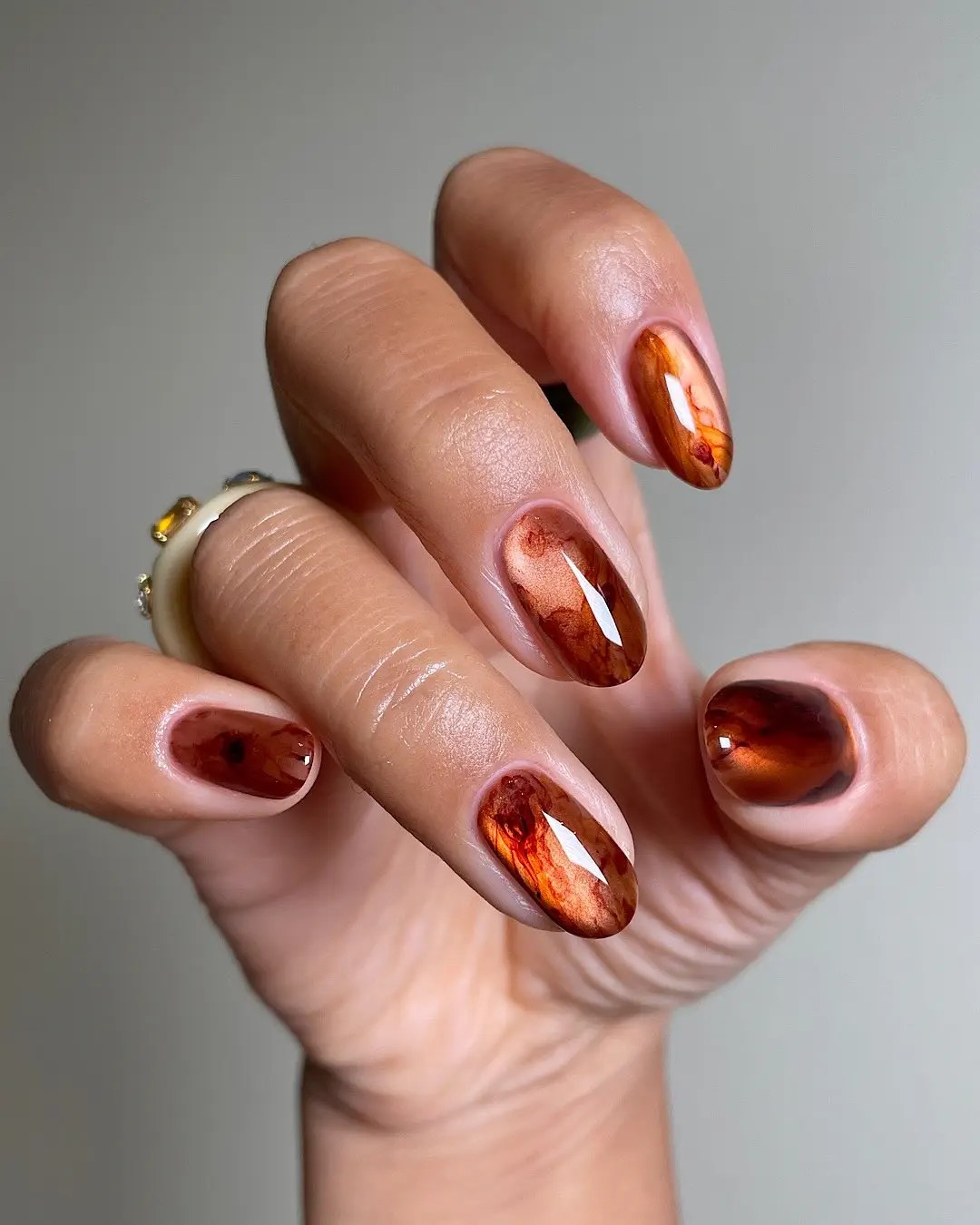Short fall classy nails in glossy amber and rust marbling that resembles polished stone