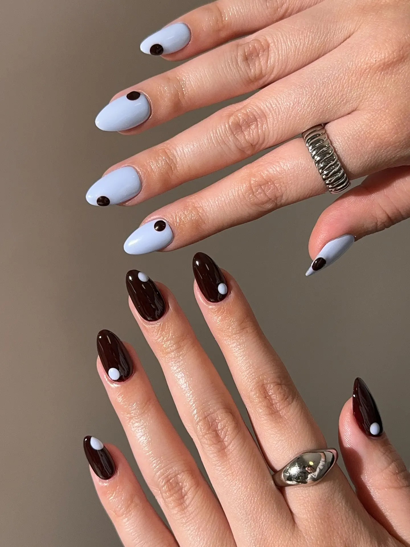 Fall simple nails with one hand in pale blue and the other in dark brown, each nail marked with a single contrasting dot at the base