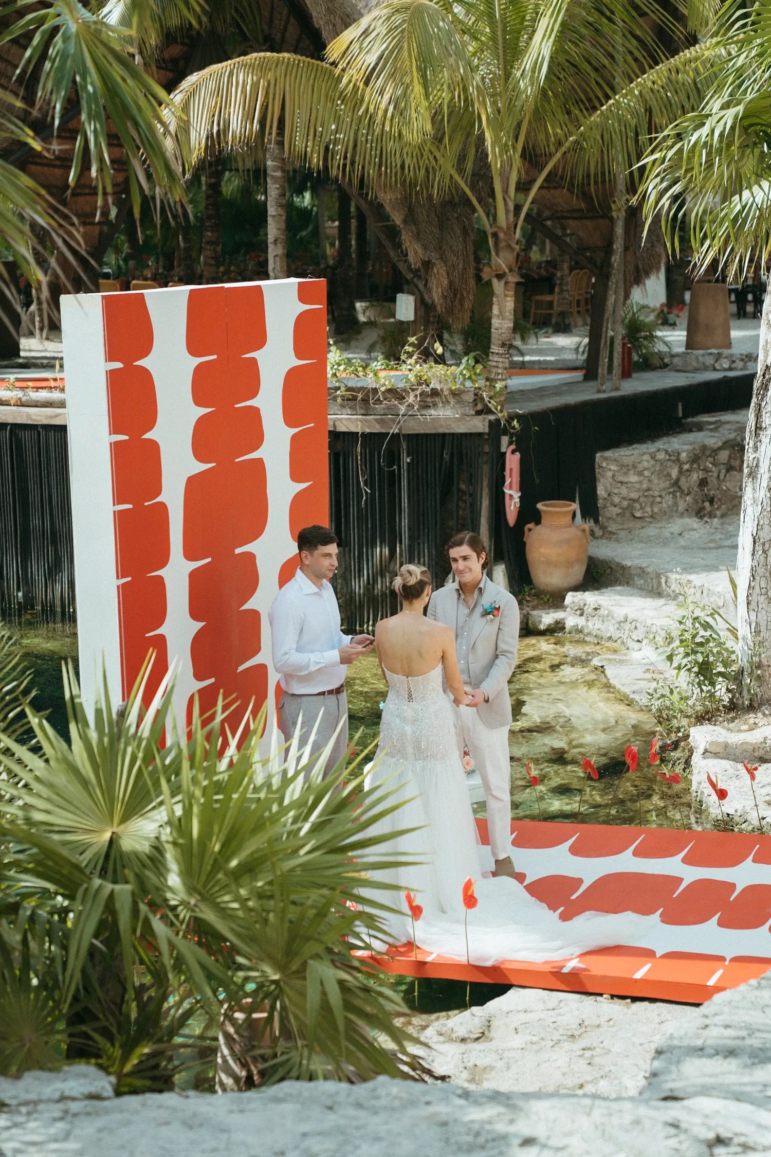 Laura and Stephen exchanging vows on the graphic red-and-white platform suspended over the cenote