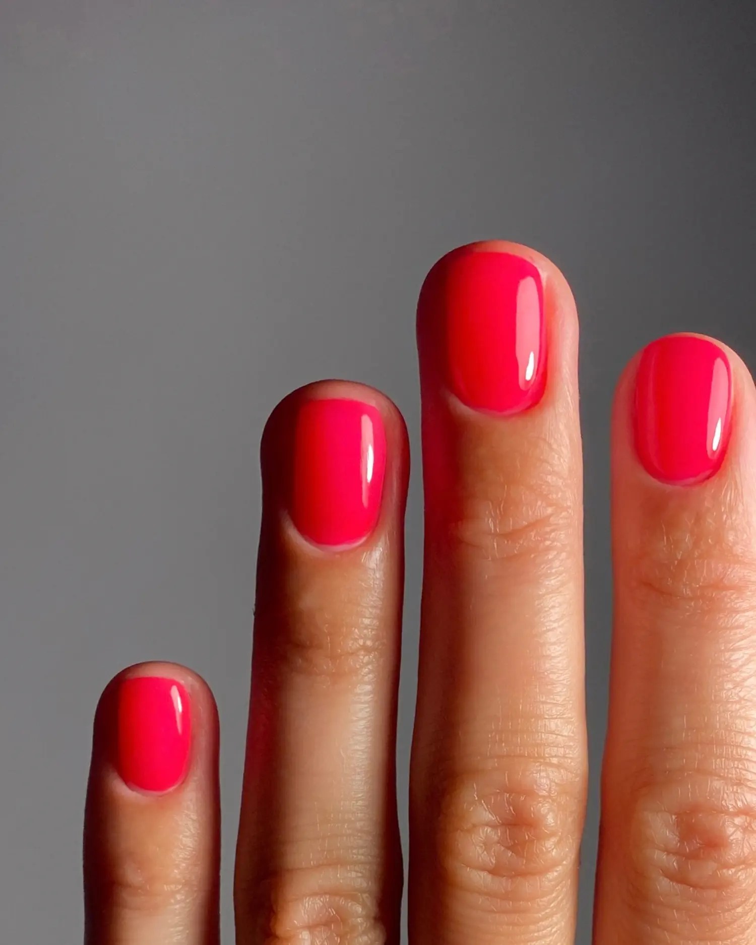 Short round sheer cherry red jelly nails with a raspberry undertone and mirror-shine finish