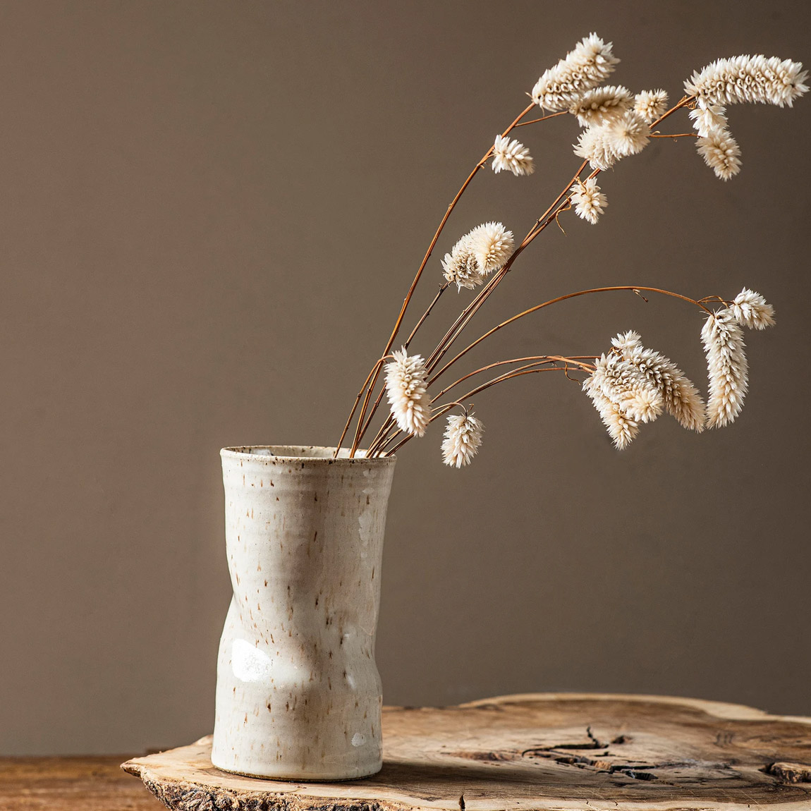 Grand vase en céramique crème contenant des branches séchées