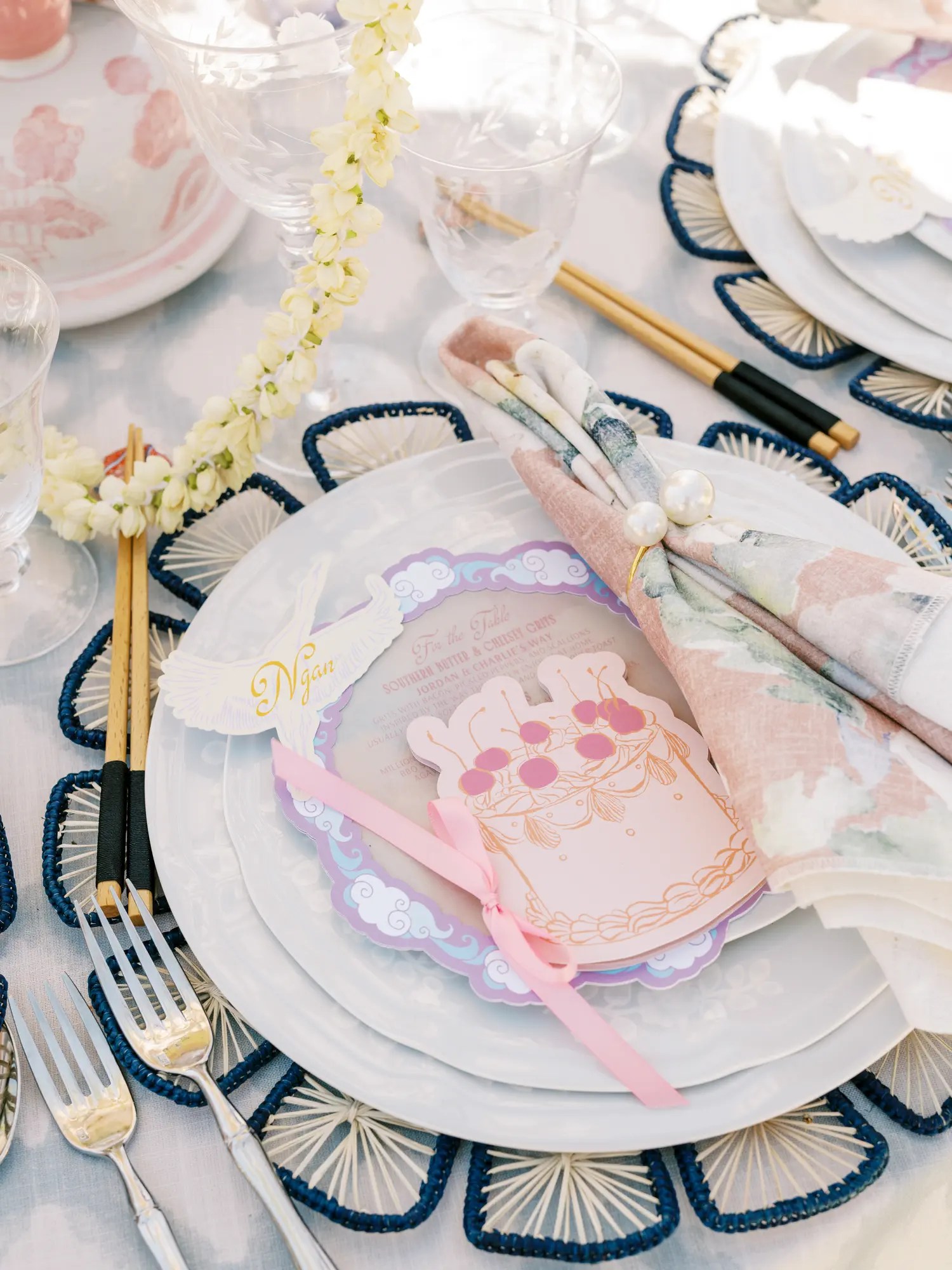 Wedding place setting with navy fan-spoke charger, cloud-border lavender menu, cherry die-cut card, pearl napkin ring, and gold-tipped chopsticks