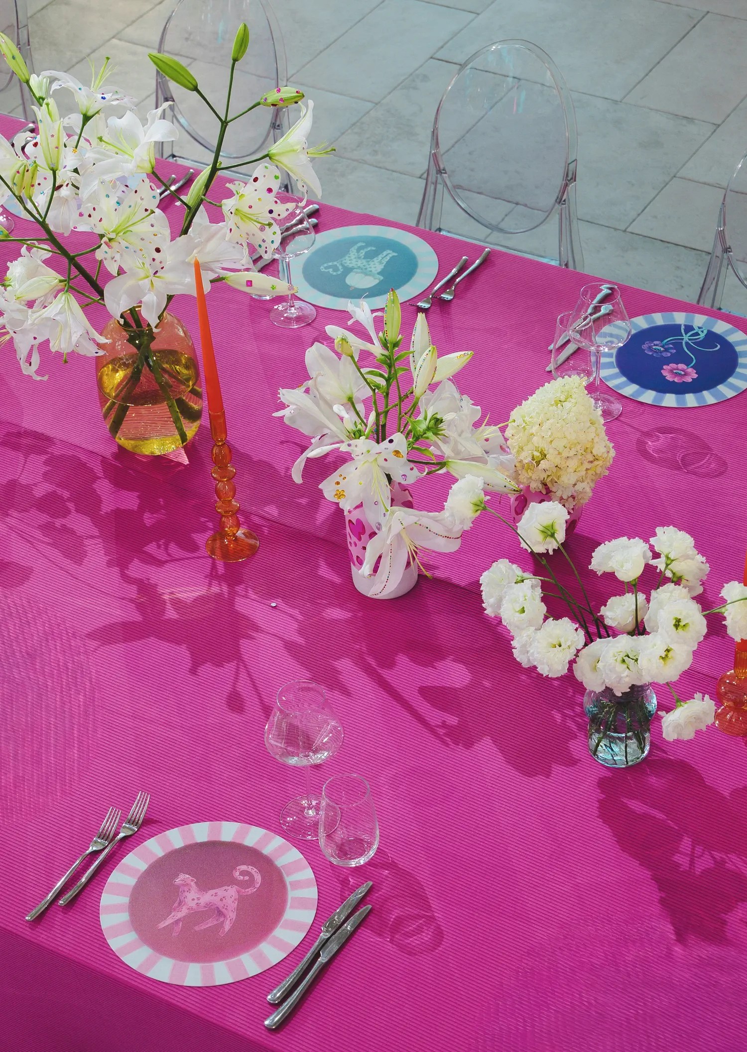Pink wedding tablescape with custom leopard charger plates, rhinestone-stickered lilies and a red taper candle in an amber glass vase