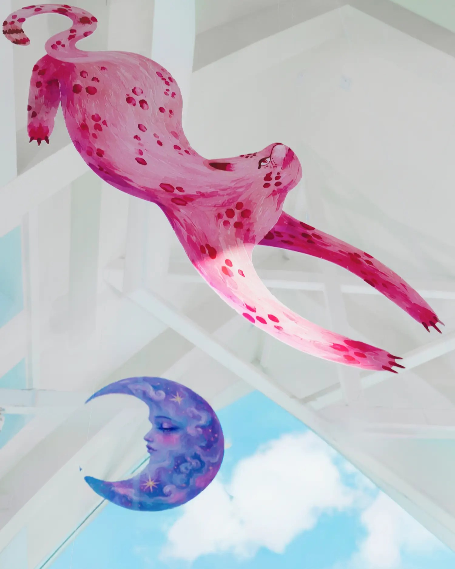 Hand-painted pink leopard and lavender crescent moon cut-outs hanging from a white geometric glass ceiling