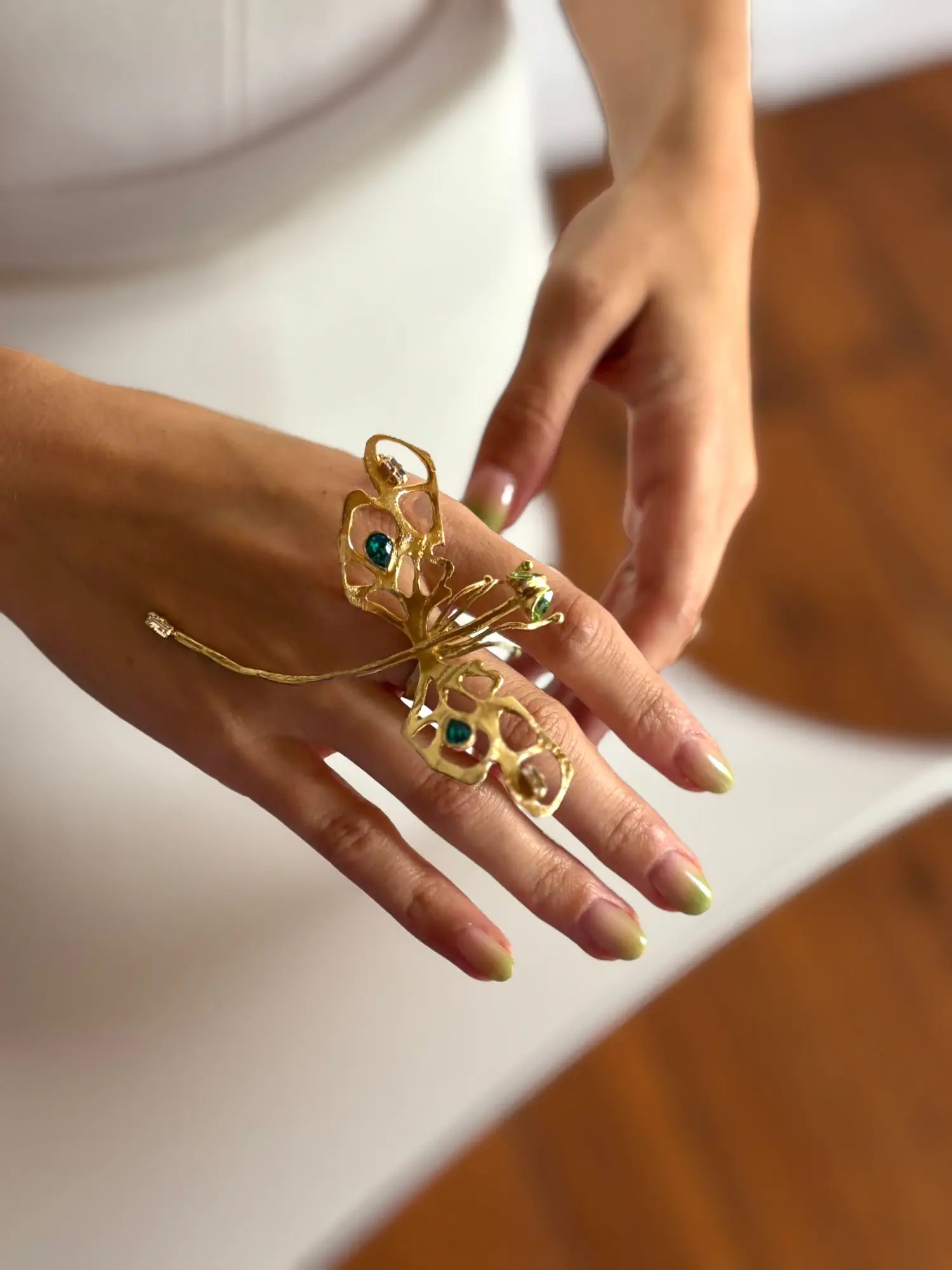 Bride's hand wearing a Kalliope gold dragonfly ring with teal stones and a lime green ombré manicure by Cult Beauty Bureau