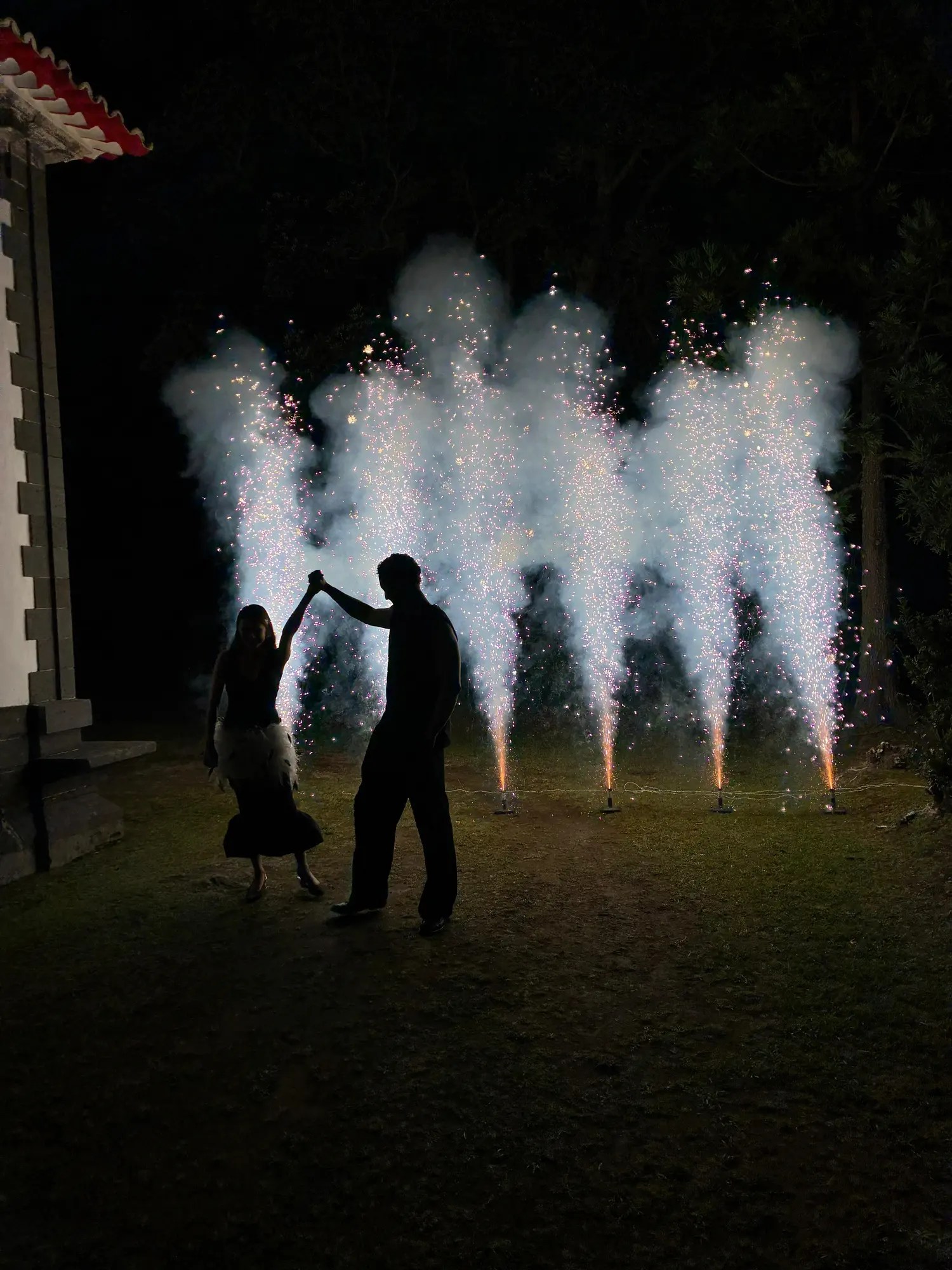 Silhouette of a couple dancing in front of cold spark fountains at night on the lawn at the Casa Grande reception in the Azores