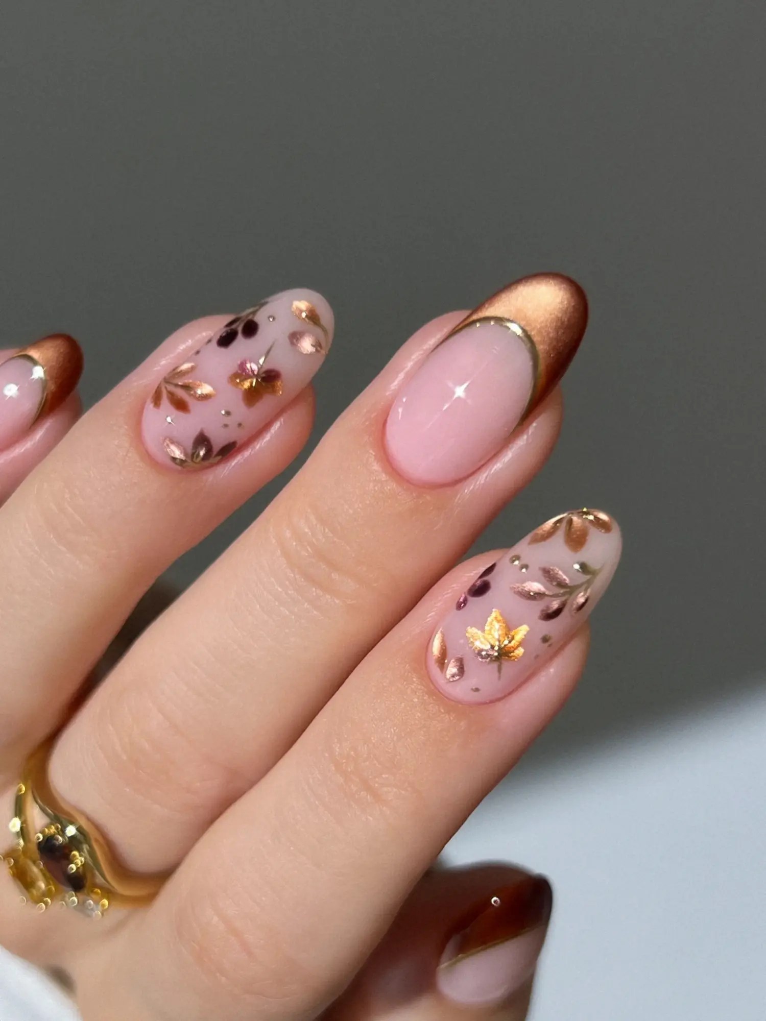Milky pink almond nails with rose gold foil leaf accent nails and copper cat-eye French tips outlined in gold.