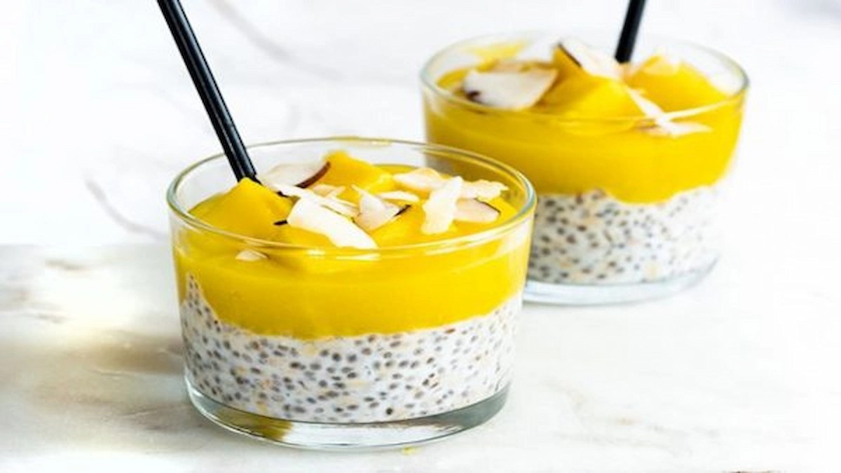 Coconut chia pudding topped with mango puree and coconut flakes in glass bowls.
