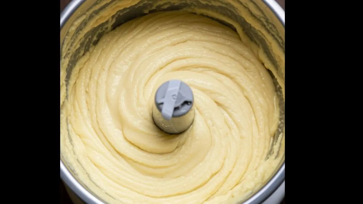 Blended hummus in a mixer grinder with a creamy, smooth texture, made by adding water gradually and scraping down the sides for even mixing.