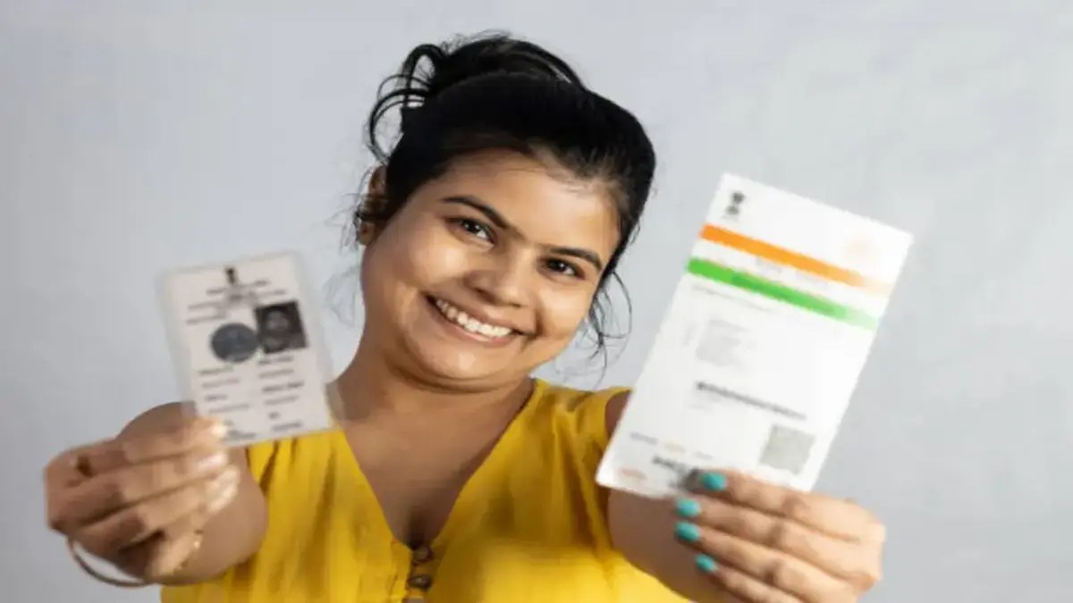 An Indian young woman smiling with Aadhaar card and voter card in hands on white background