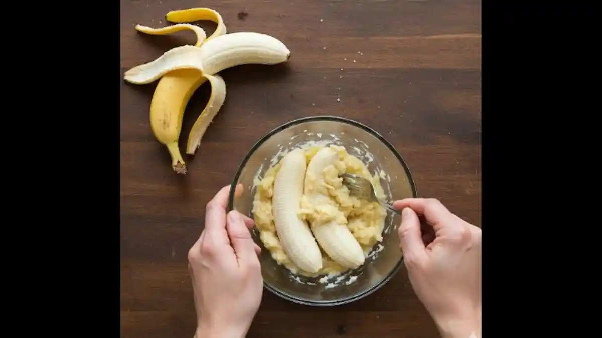 A bowl of ripe bananas being mashed with a fork until smooth, ready for use in cake batter.
