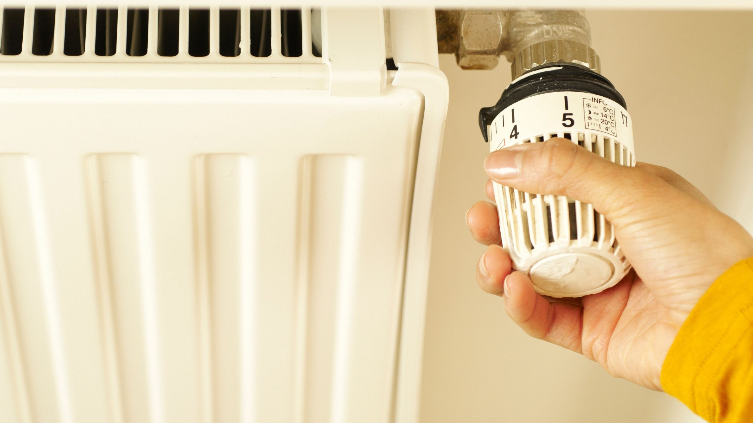 Hand adjusting the temperature control on a household radiator