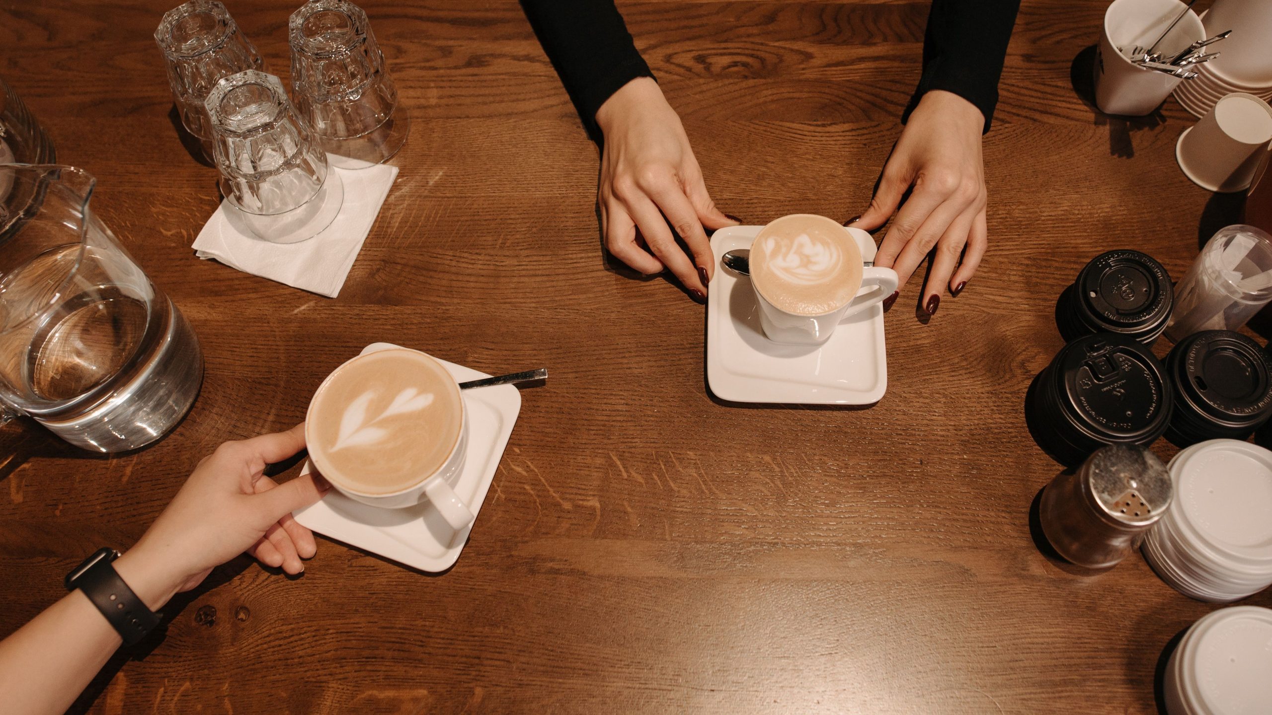 Two people sitting across a cafe table with coffee during a conversation