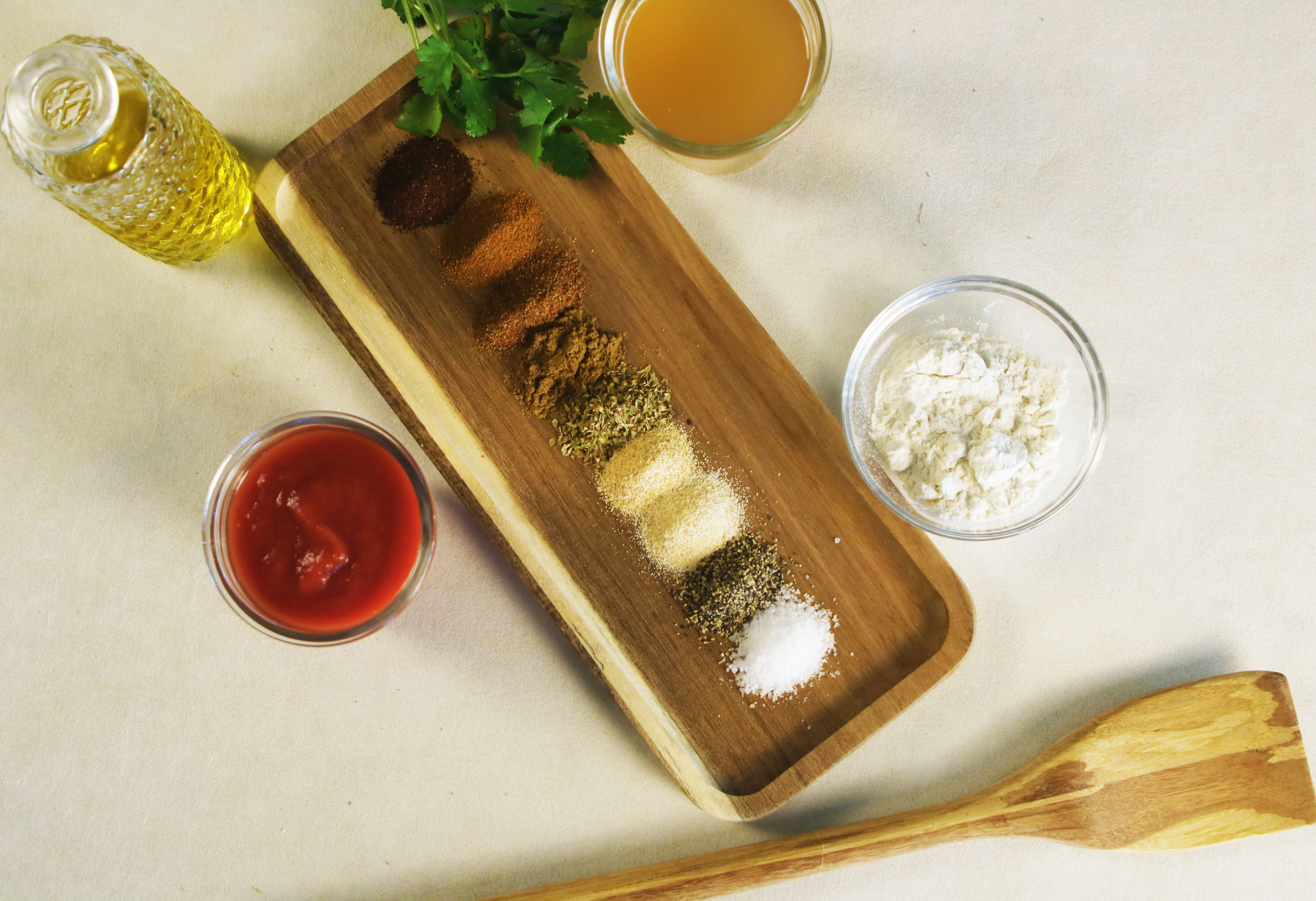  Ingredients for homemade red enchilada sauce displayed neatly—tomato paste, flour, seasonings, oil, broth, and fresh cilantro