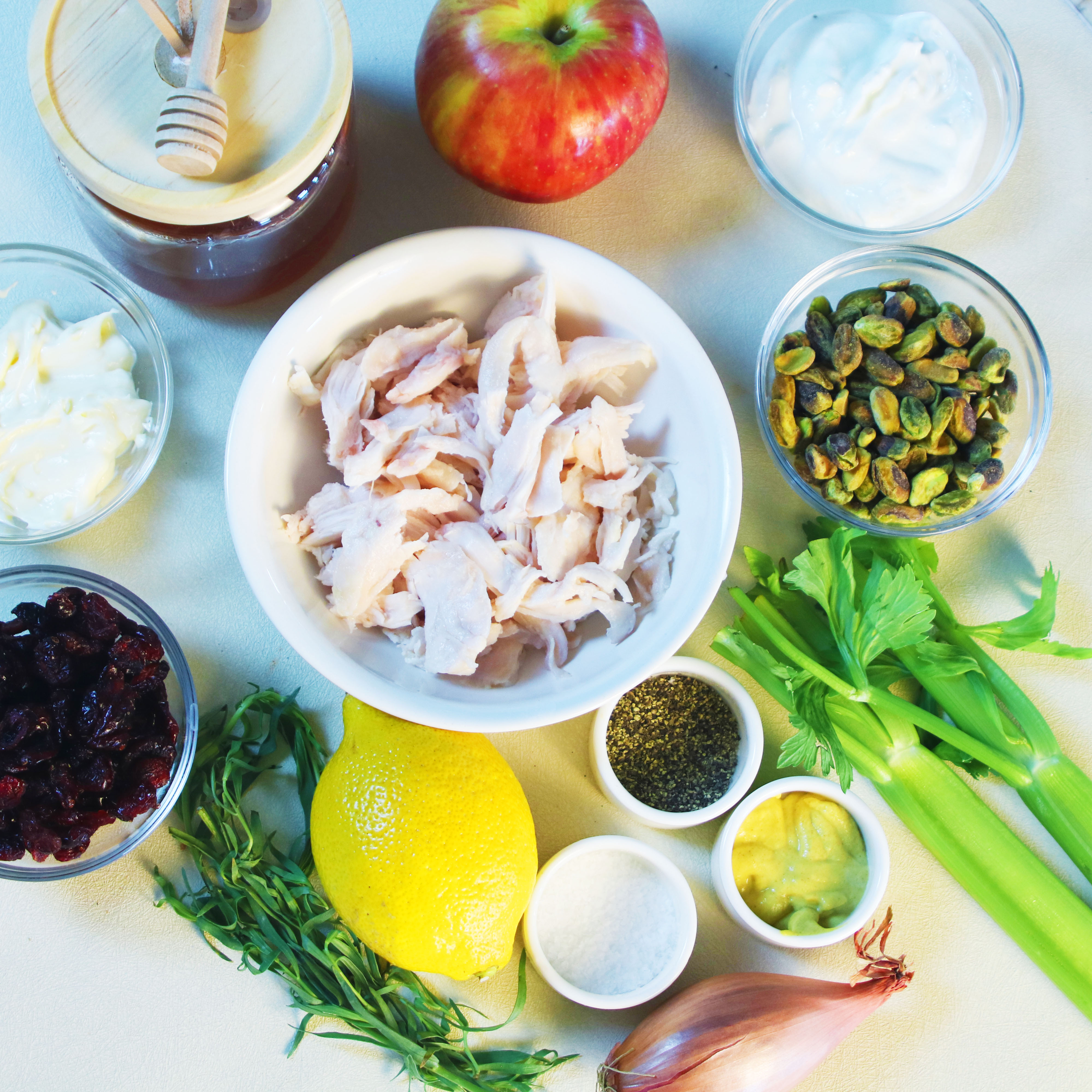 Ingredients for cranberry apple chicken salad including chicken, apples, pistachios, celery, cranberries, lemon, yogurt, mayonnaise, tarragon, and mustard.