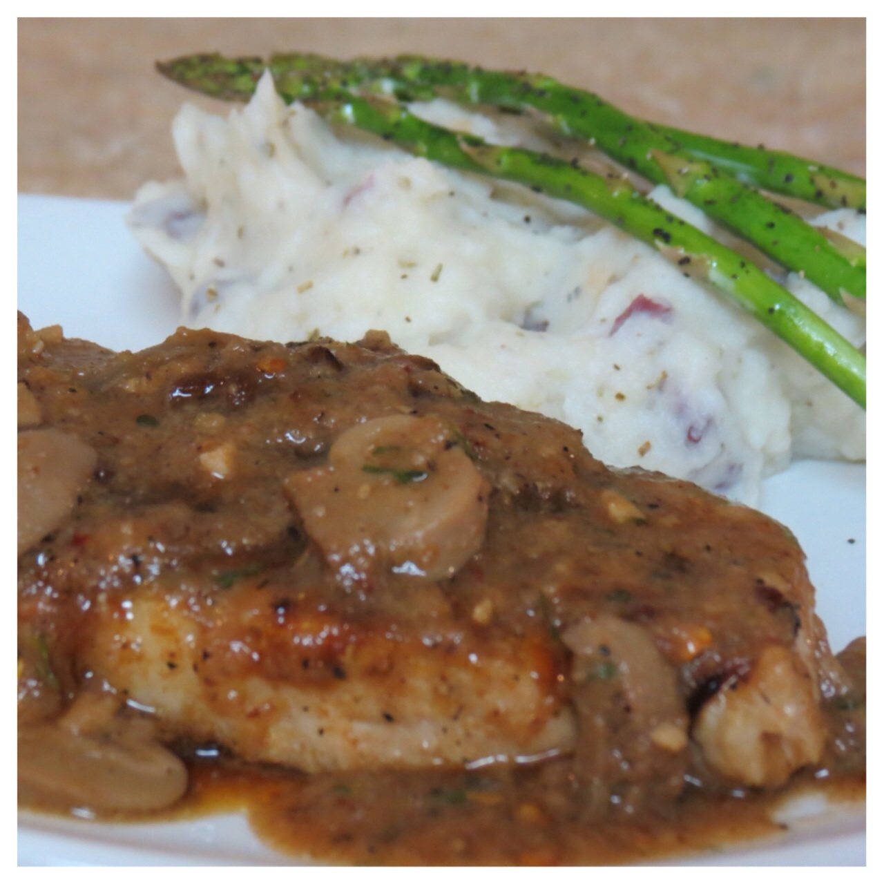Pork chops with a red wine ams mushroom gravy, red mashed potatoes, and asparagus