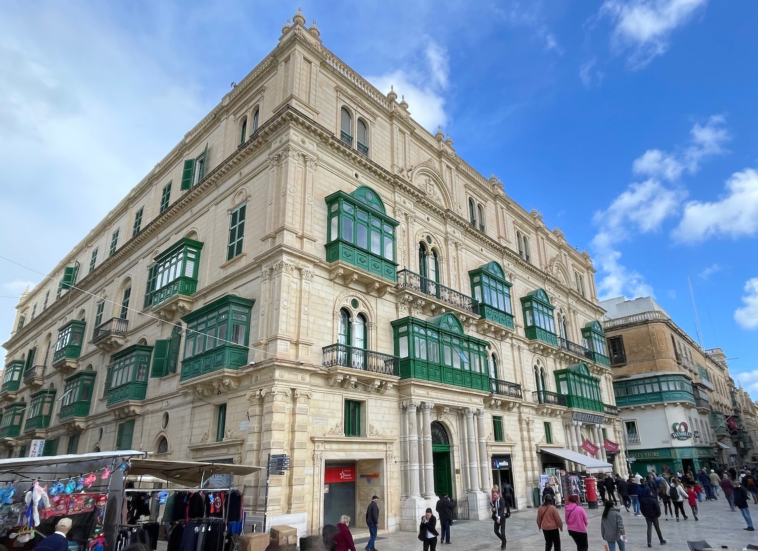 A large cream-colored bulding with distinctive green wooden balconies
