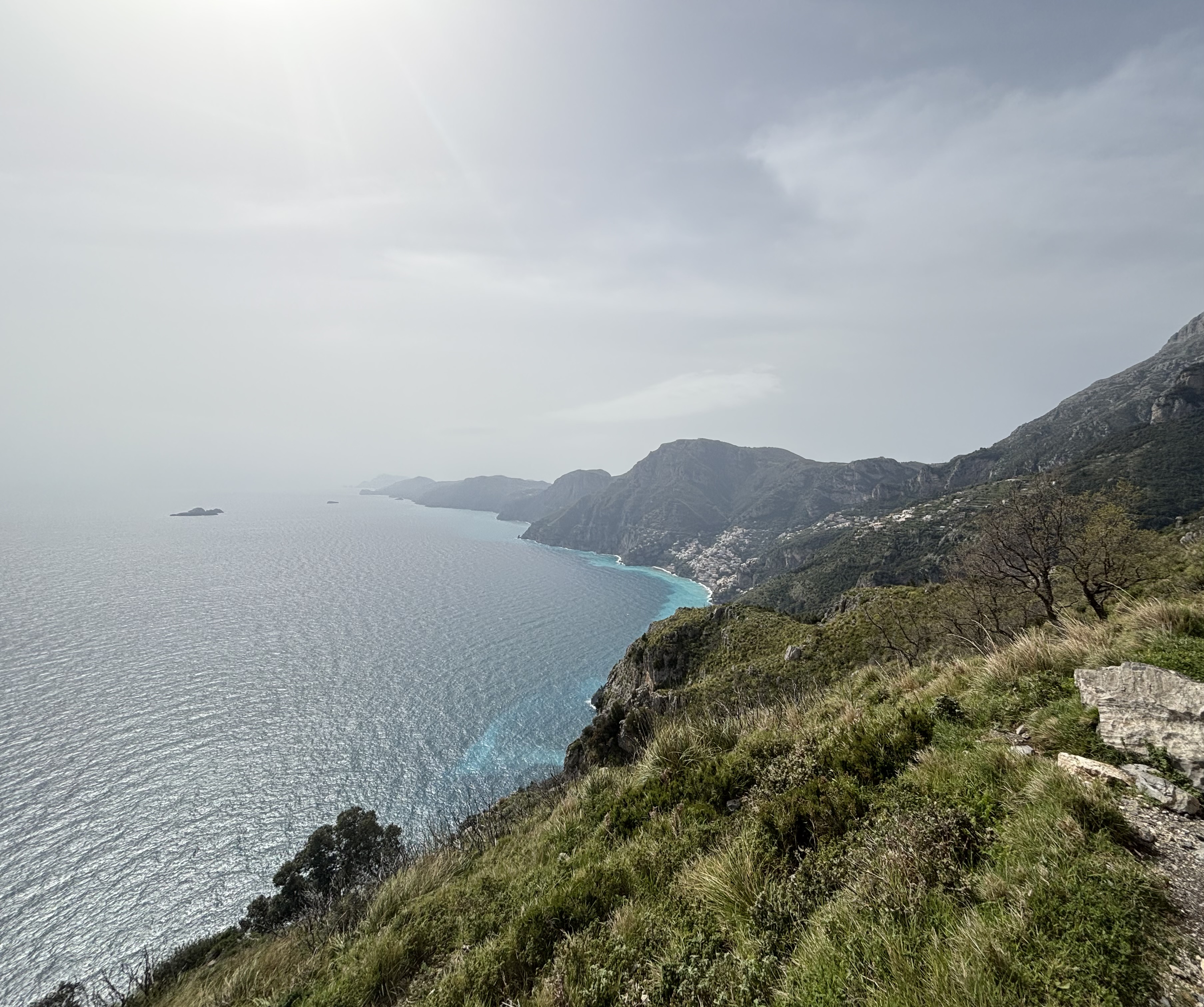 Das Bild wird durch die ruhige Weite des Meeres und die im Hintergrund aufragenden Berge geprägt, wodurch eine harmonische und zugleich eindrucksvolle Naturlandschaft dargestellt wird.