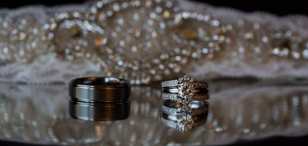 The Importance of Detail Photos: Rings, Florals & Personal Touches by GSquared Weddings Photography Seattle Snohomish Snohomish Wedding Photographer GSquared Weddings A black wedding band and a sparkling diamond engagement ring with a matching wedding band are displayed in exquisite detail on a reflective surface. The background features an ornate, beaded design. Serving Seattle, Snohomish and Orlando