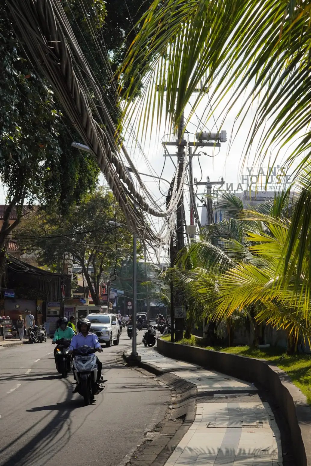 Foto de palmeras, cables y motos en el centro de Kuta, Bali en Indonesia