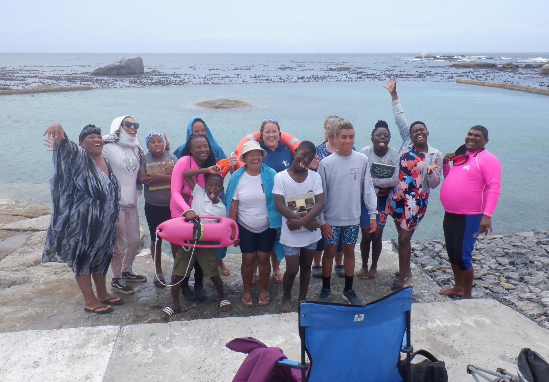 A diverse group of adults and children standing together at a tidal pool for a Project KNEXS educational outing.