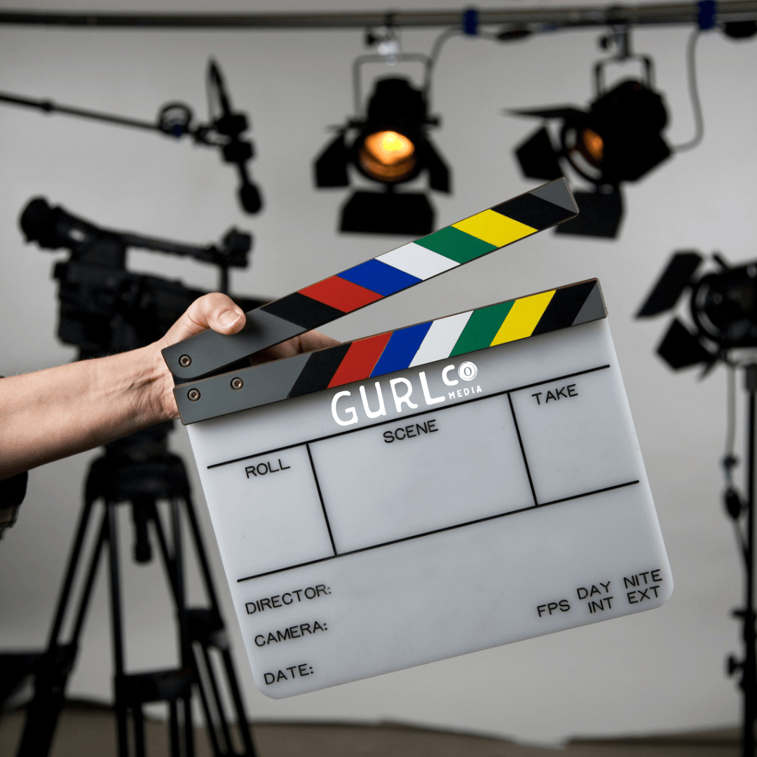 A branded GurlCo Media director clapperboard on a professional commercial video production set with studio lighting.