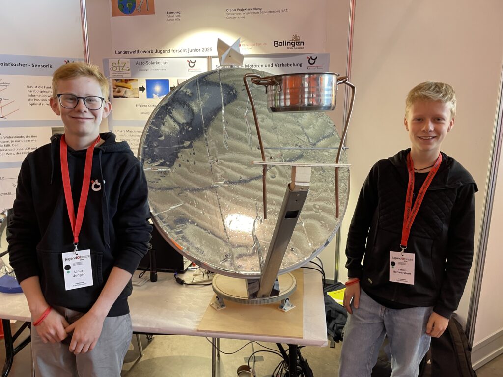 Zwei Schüler stehen vor ihrem Jugend-forscht-Projekt, einem Solarkocher aus einer ausgedienten Satellitenschüssel.