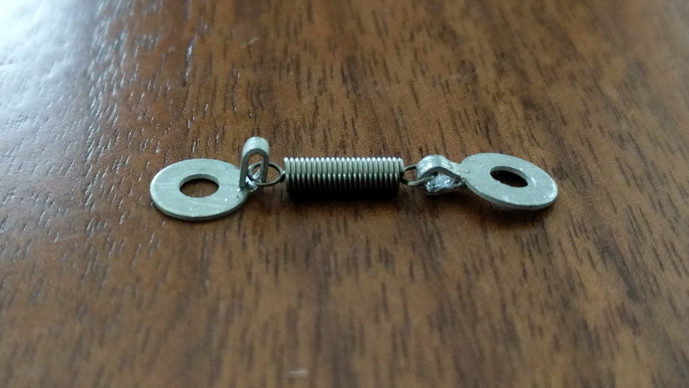 An extension spring looped between two terminal lugs