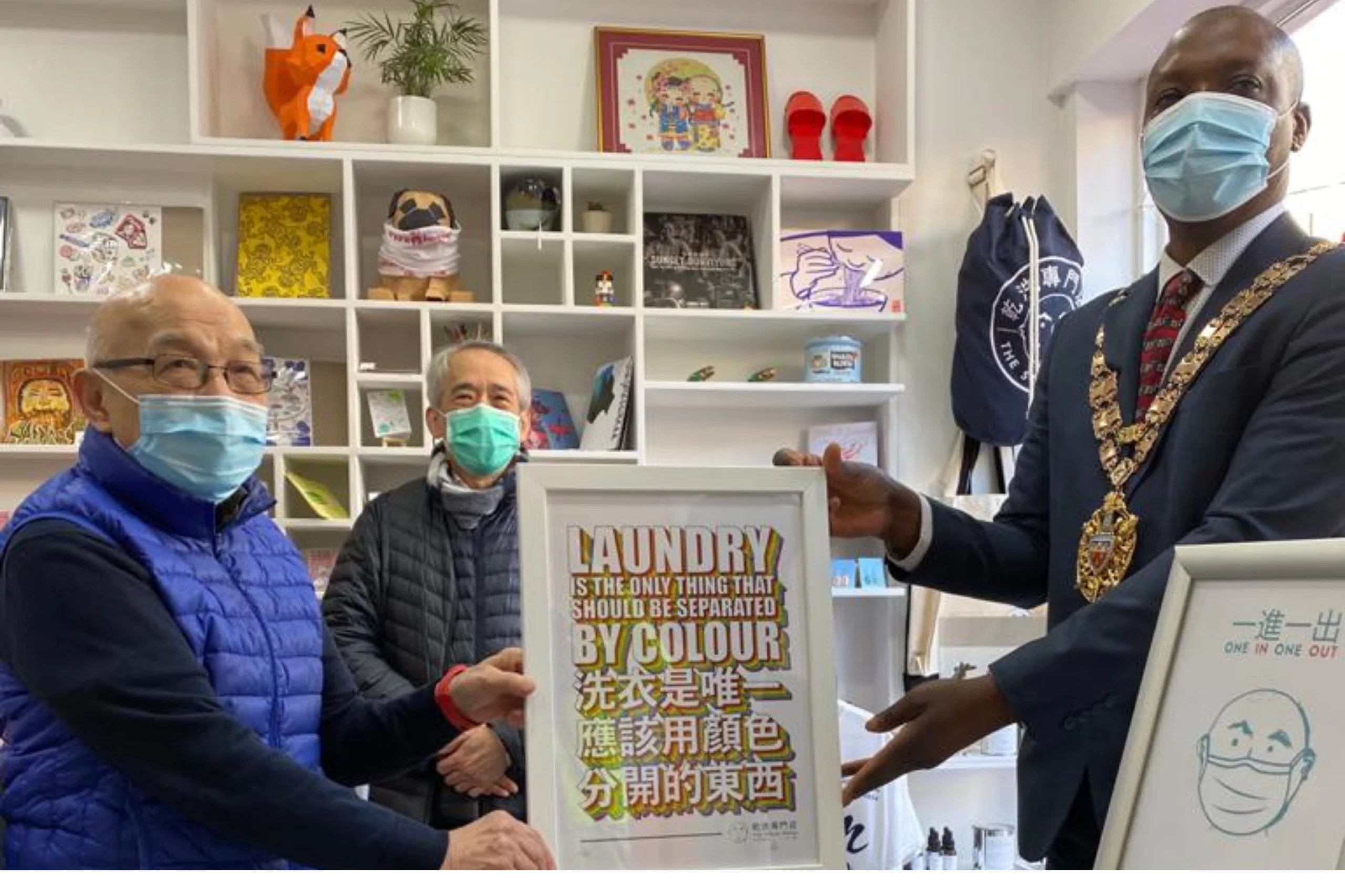 Speaker of Hackney and Tony Chung holding a framed picture that says: “Laundry is the only thing that should be separated by colour.”