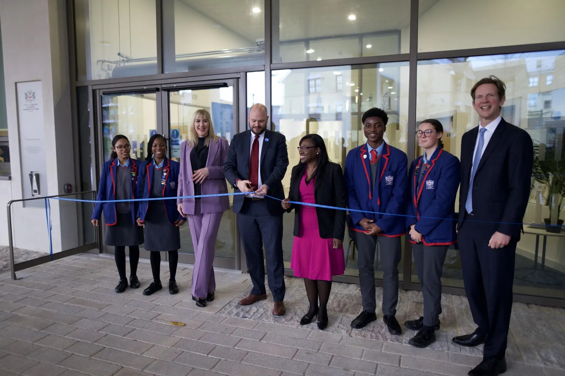 Photo depicts Mayor and school children cutting ribbon for new building