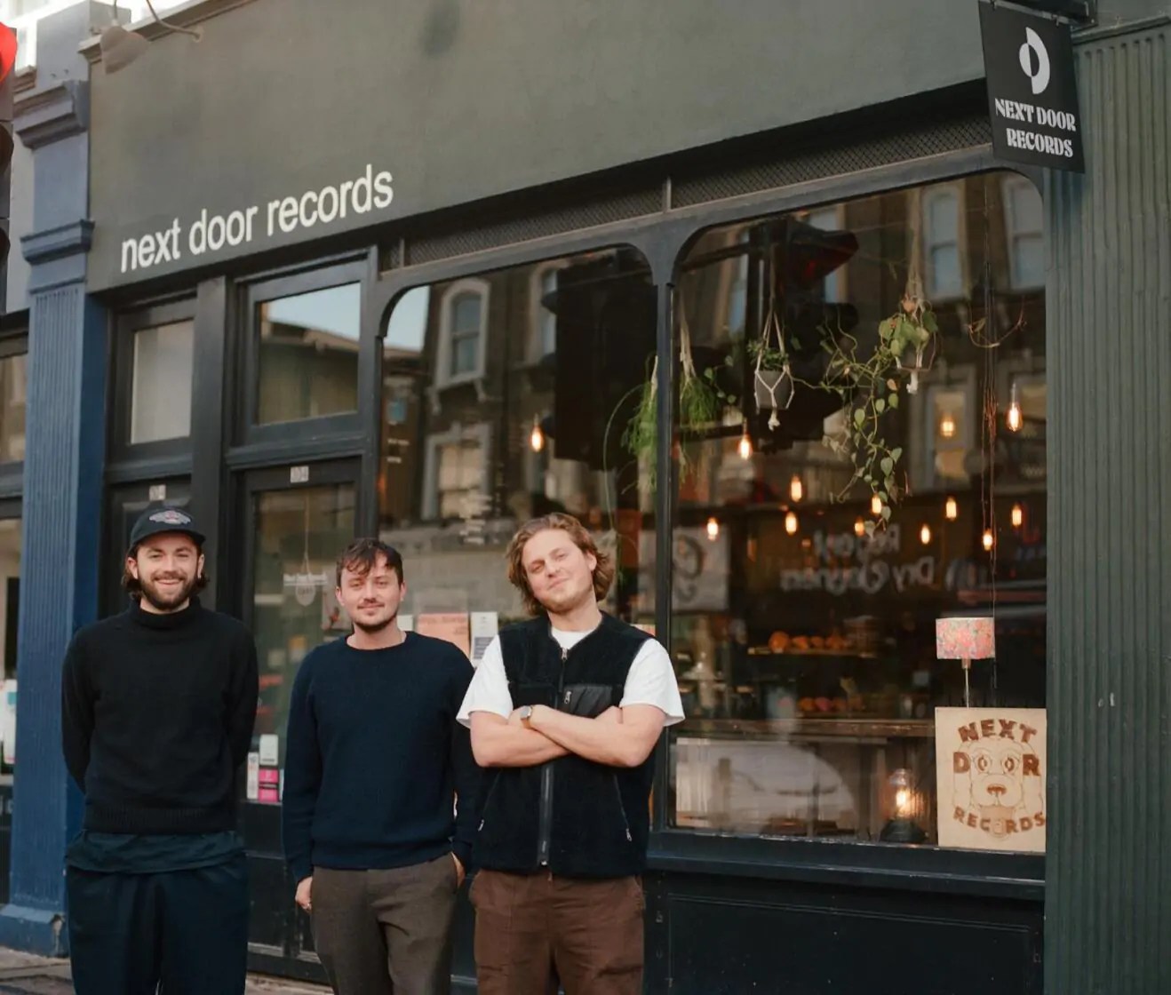 three men standing outside a shop